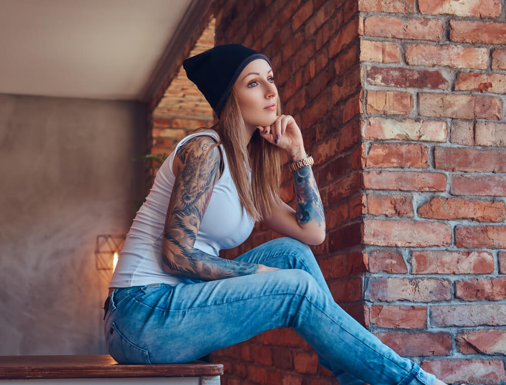 A stylish tattooed blonde female in t-shirt and jeans