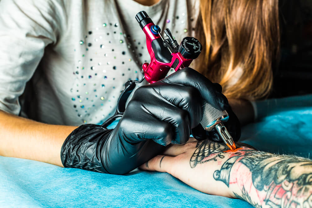 Master tattoo draws orange paint on clients hand