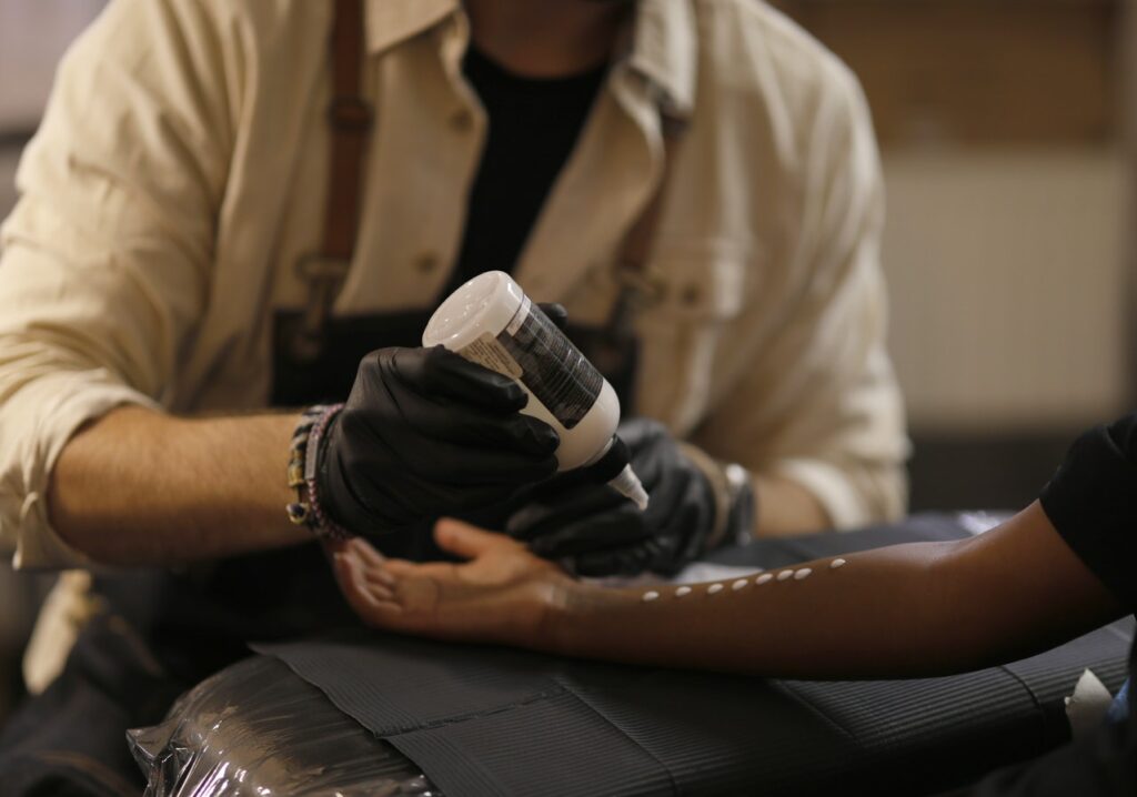 Unrecognizable crop male tattooist preparing arm of client in modern salon